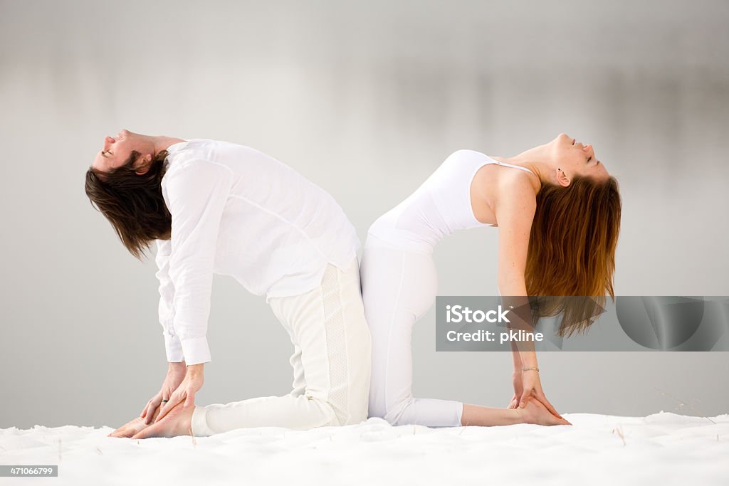 Casal fazendo Yoga "Postura do Camelo" na neve - Foto de stock de 20 Anos royalty-free