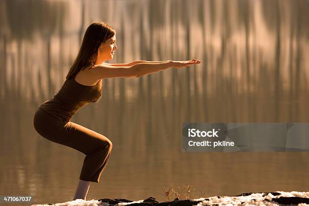 Mujer Hace Yoga Pose Silla Junto Al Lago Foto de stock y más banco de imágenes de 20 a 29 años - 20 a 29 años, Actividades y técnicas de relajación, Adulto