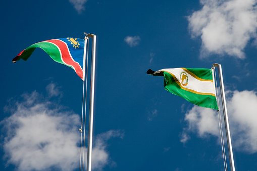 Namibia Flag and Flag of the African Union together against blue summer cloudscape in the wind.