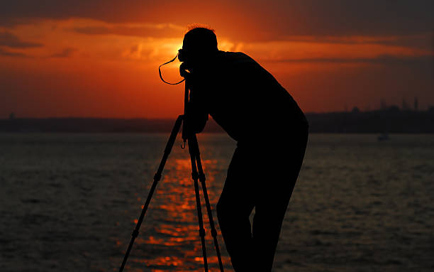 istock silhouette photographer focusing the sunset 471074373