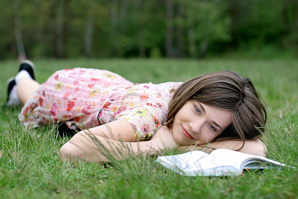 istock young girl is laying on the grass with a book 471074825