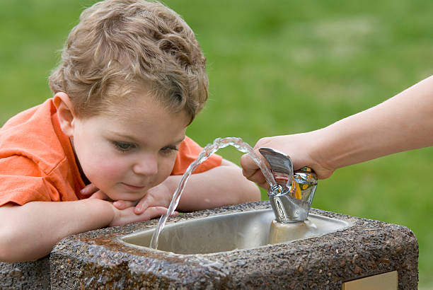 istock Brother Helps Toddler With Drinking Fountain 471075691