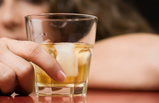 Glass of whiskey and a woman in the very shallow depth of field