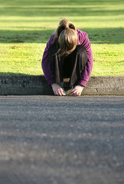 girl sad girl over green grass, more with the same model: sad girl crouching stock pictures, royalty-free photos & images