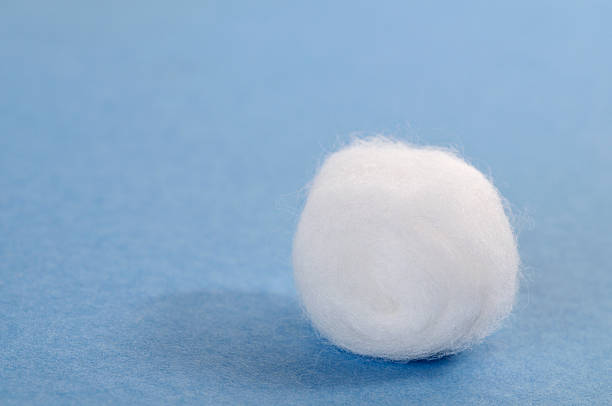 Single cotton ball on blue A cotton ball on a textured blue background cotton ball photos stock pictures, royalty-free photos & images