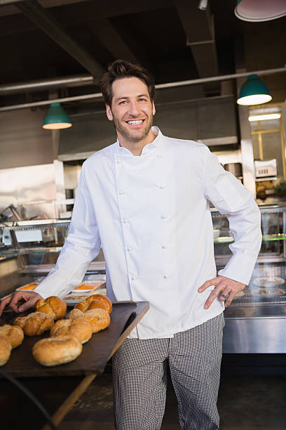 istock Happy baker standing near tray with bread 471081008