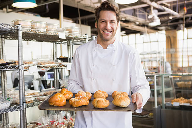 istock Cheerful baker holding tray of bread 471081022