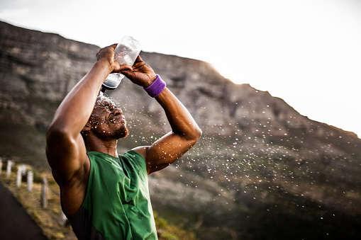 Athlete splashing himself with water from his water bottle after a hard morning run
