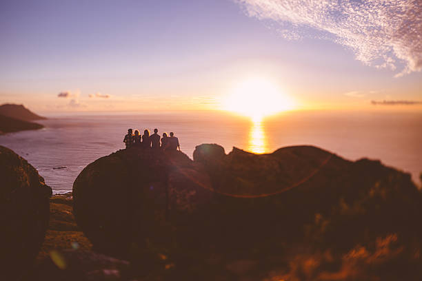 istock Silhouetted friends on a mountain watching a sunset over ocean 471081156
