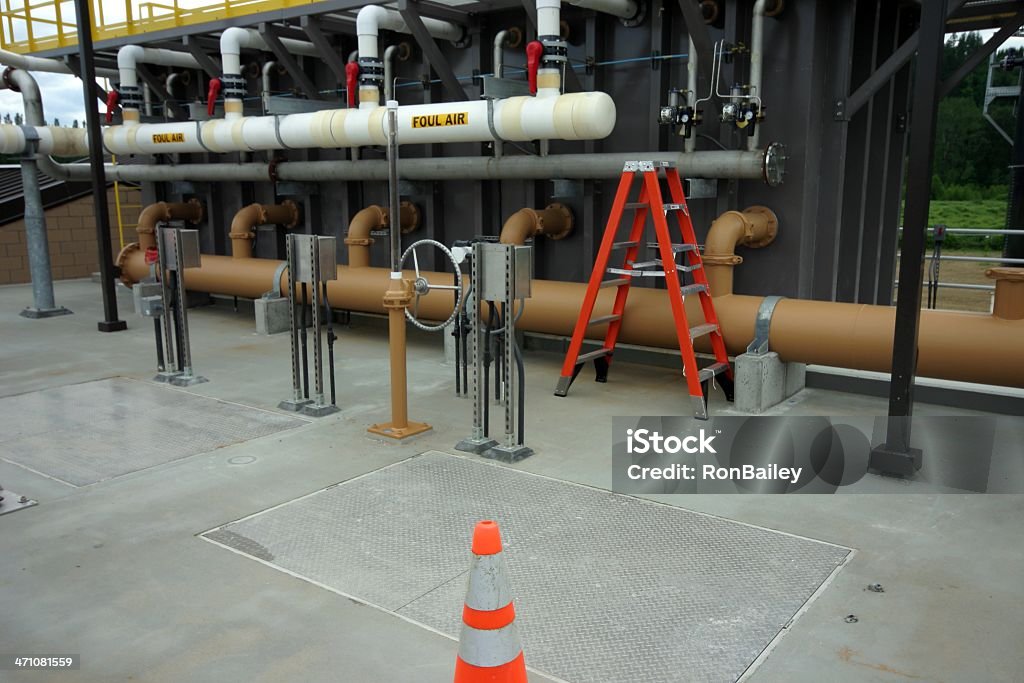 Wastewater Treatment Plant Pipes, valves, aeration tanks and  membrane filter of a newly constructed wastewater treatment plant.  Sign on white pipes says "FOUL AIR". Aeration Lagoon Stock Photo