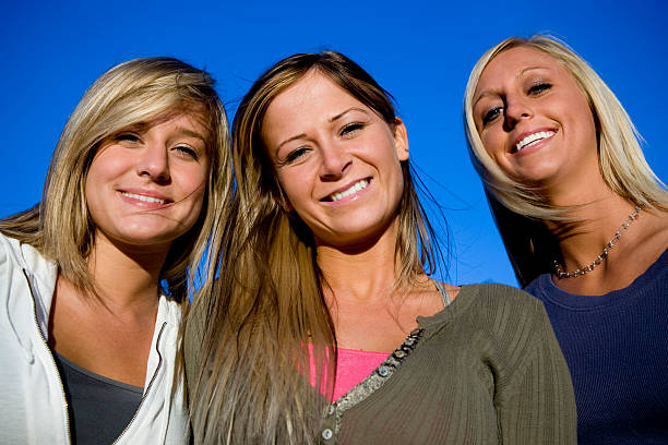 Cheerful Girls against blue sunny sky, happy and having fun. Girls Group Shot.