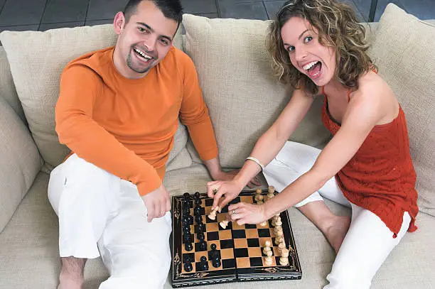 Photo of Young couple playing chess at home in the living room