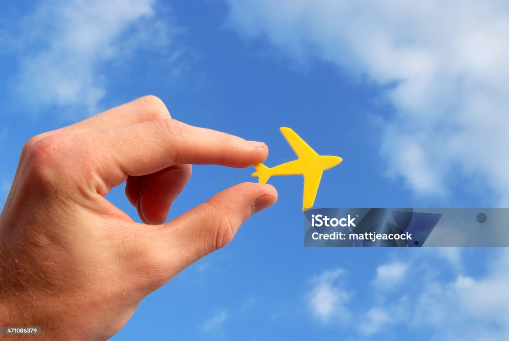 Mão segurando pequeno Amarela avião contra o céu azul - Foto de stock de Amarelo royalty-free