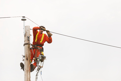 A lineman works on a pole.  Click to view similar images.