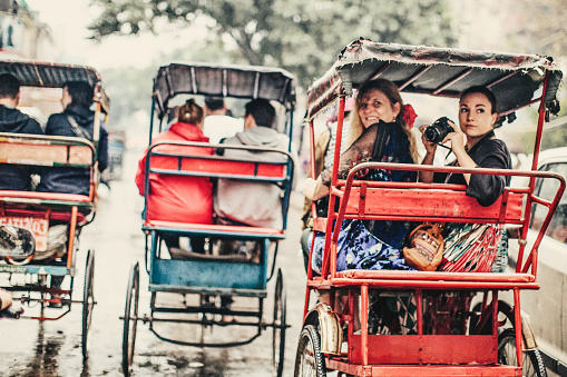 Two photographers enjoying a rickshaw ride in Old Delhi, India.