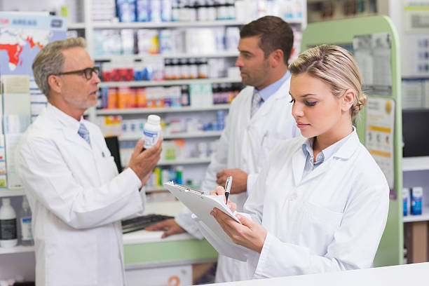 istock Pharmacist woman writing on clipboard and men talking 471088978