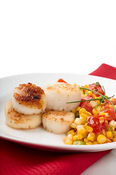 Pan-seared New England bay scallops served with a hash of tomato, corn and edamame.