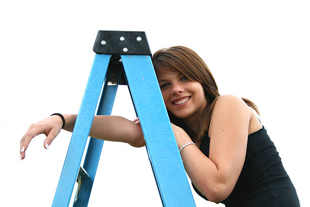 Woman on top of folding ladder looks across a wall.