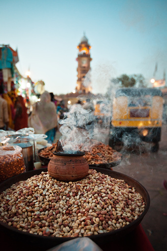 Close up of roasted peanuts in big bowl at street market in Jodhpur, India, Rajasthan. India rikshaw in the background.