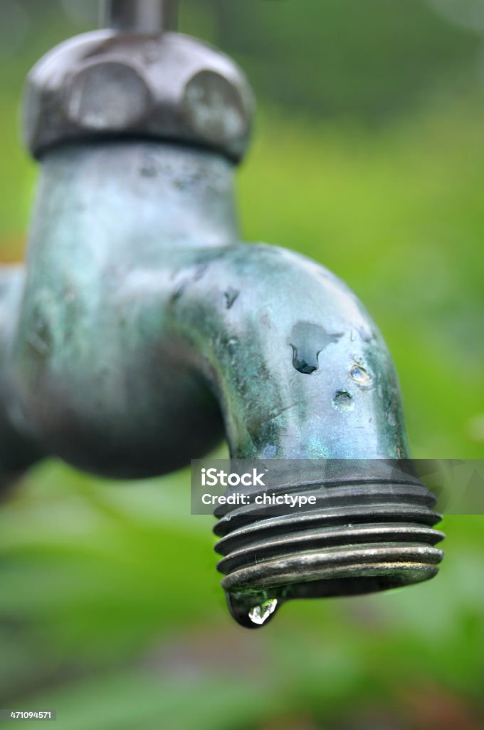 Leaking Faucet Drop of water leaking from an old faucet.  Close-up Stock Photo