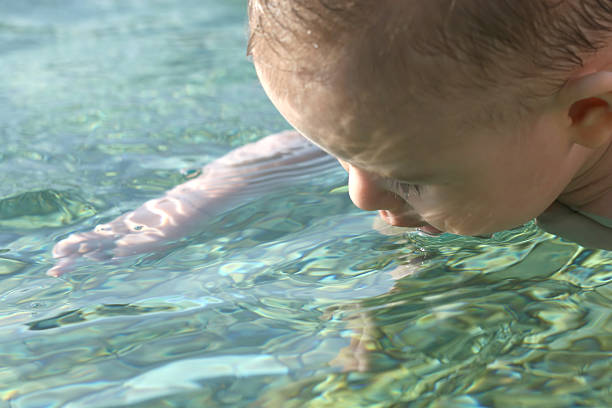 View of a baby boy playing at Mediterrian Sea in the summertime.The baby boy six months old. His mother is keeping him on the water with mother care.
