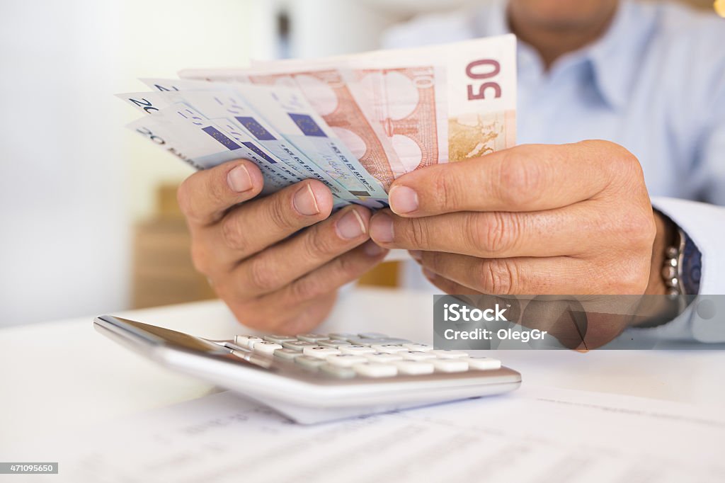 A man counting paper bills with a calculator Accounting European Union Currency Stock Photo