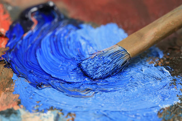 Paintbrush with blue oil paint on a classical palette