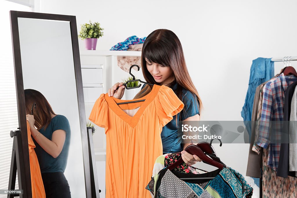 Beautiful young woman near rack with clothes Beautiful young woman near rack with clothes making chioce Clothing Stock Photo