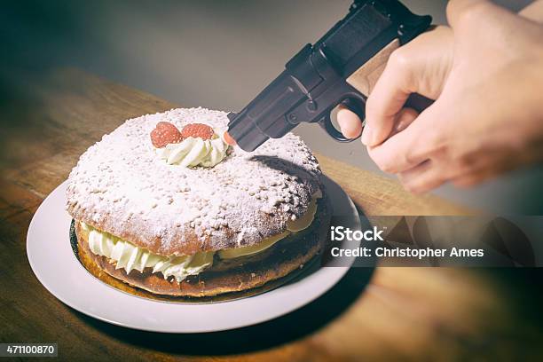 Woman Threatens Delicious Cream Cake With Toy Hand Gun Stock Photo - Download Image Now