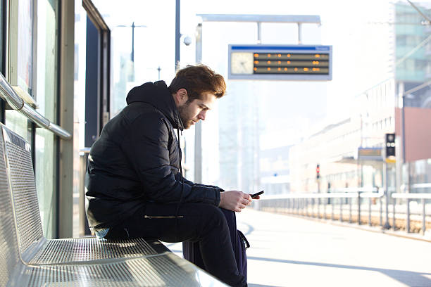 istock Man at train station platform with mobile phone 471101380