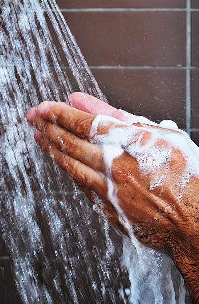 Man in Shower Man rinsing soap off hands in the shower. shower men falling water soap sud stock pictures, royalty-free photos & images