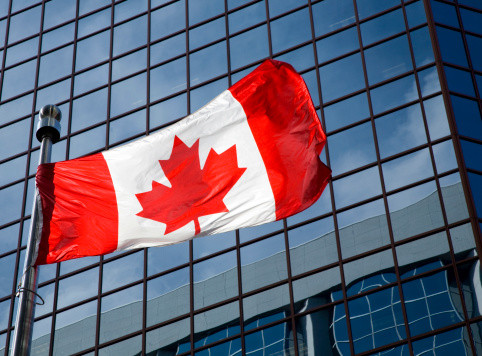 canadian flag in front of modern building