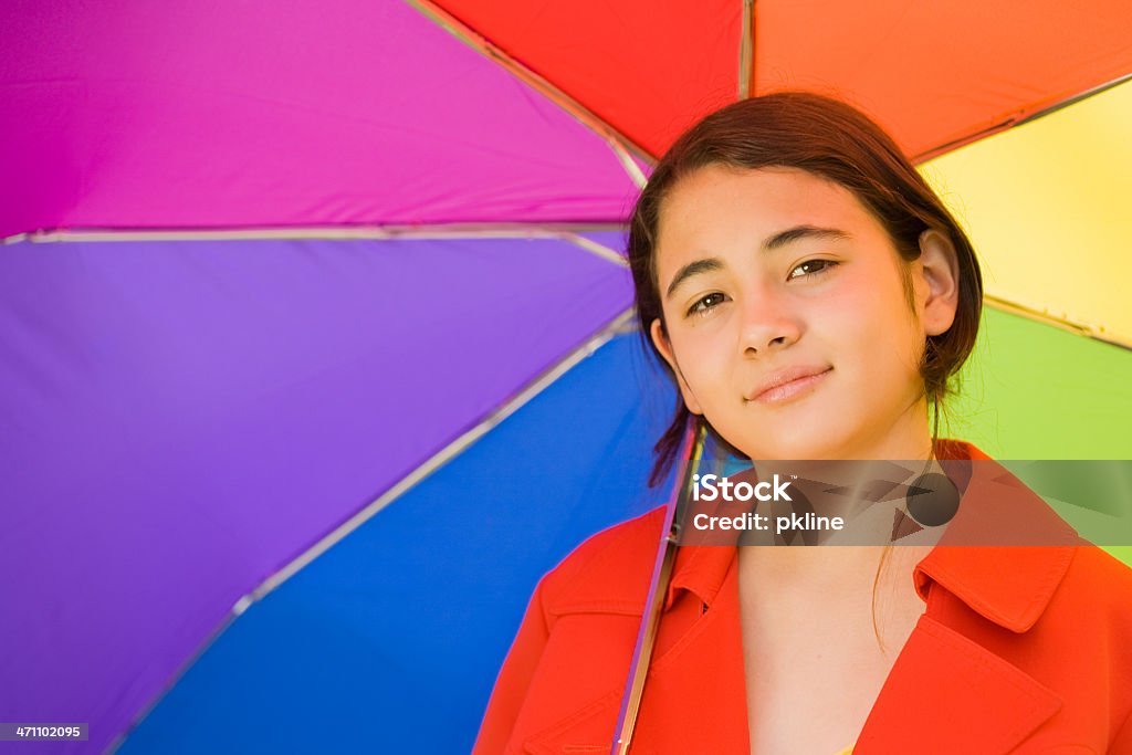 Close-up of Asian-American teen girl with multicolored umbrella Close-up of Asian-American girl in red raincoat under a multicolored umbrella 14-15 Years Stock Photo