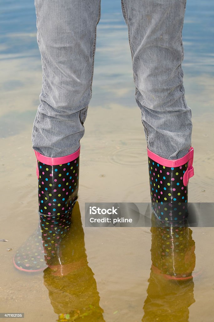 Girl pruebas su polka dot galoshes de agua superficiales - Foto de stock de 14-15 años libre de derechos