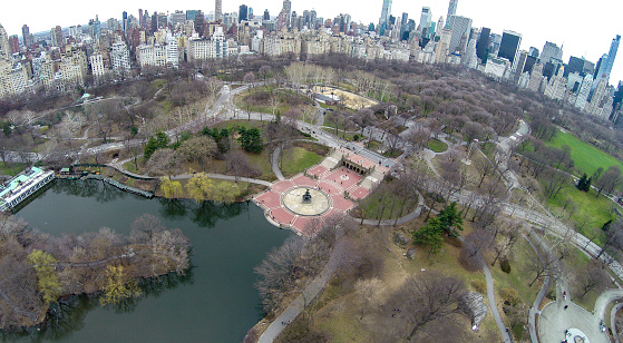 Aerial view of Central Park with Bethesda Fountain, Literary Walk, Sheep's Meadow  in frame, and also midtown Manhattan's skyscrapers and east side residential buildings