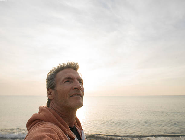 istock Man gazes off from pebble beach, at sunrise 471104770
