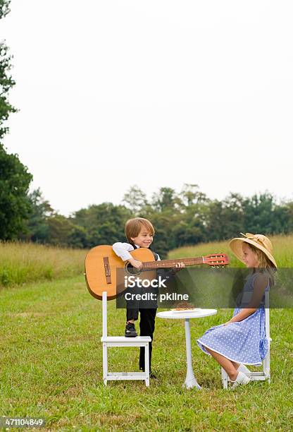 Photo libre de droit de Petit Garçon Avec Un Pied Sur Une Chaise Joue De La Guitare Pour Fille banque d'images et plus d'images libres de droit de 6-7 ans