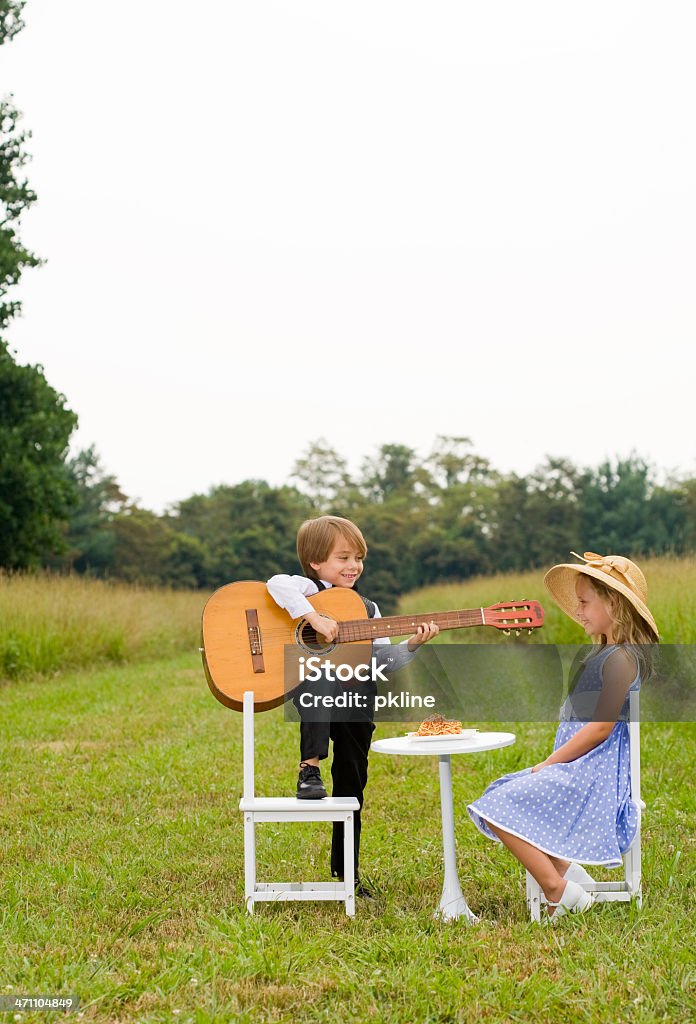 Rapaz com os pés na cadeira desempenha guitarra para rapariga - Royalty-free 6-7 Anos Foto de stock