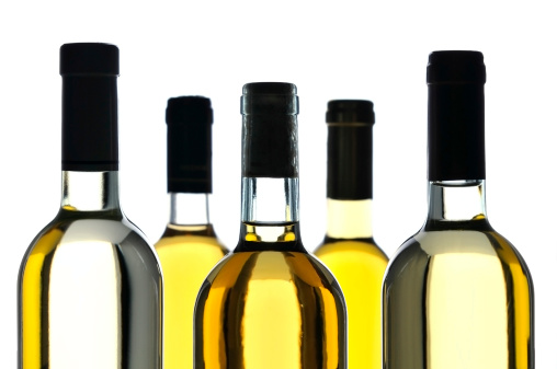 Close-up of five bottles of white wine isolated on white background, studio shot.