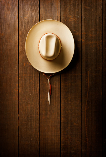 Cowboy hat hanging on side of a barn
