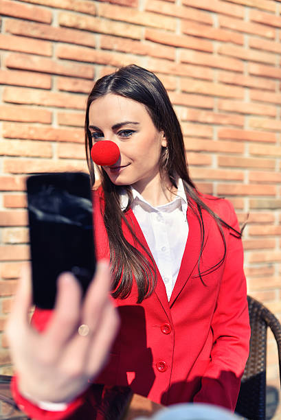 mujer de negocios con nariz de payaso tomando autofoto - curtain red color image clown fotografías e imágenes de stock