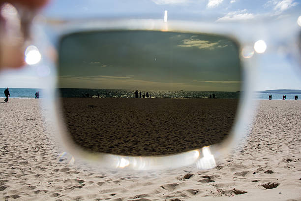 View of people enjoying the beach through sunglasses stock photo