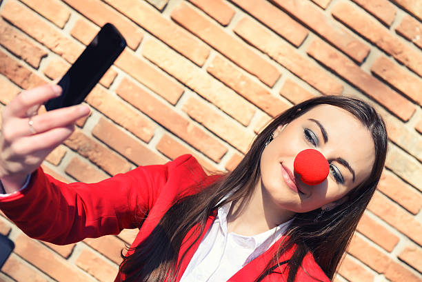donna d'affari con clown naso e fanno selfie - curtain red color image clown foto e immagini stock
