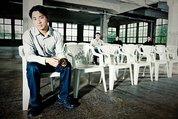 Urban Young Men Group Portrait Young men sitting in white chairs in empty abandoned warehouse. Urban Lifestyle Group Portrait. boy band stock pictures, royalty-free photos & images