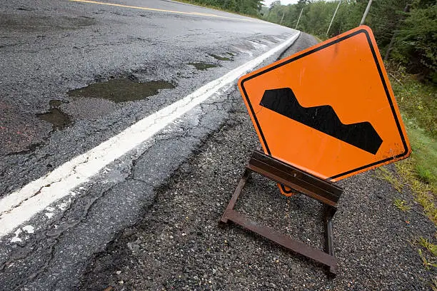 A "bump" sign sits beside a poor quality road.