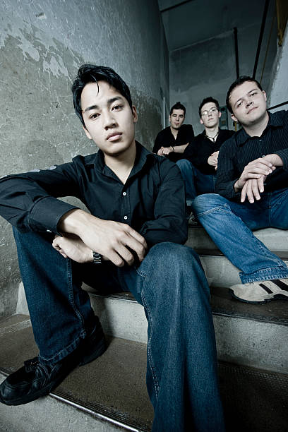 Urban Youth Group Portrait Group of young men sitting on the stairway inside an industrial warehouse. Urban Youth, Wide Angle Group Portrait. boy band stock pictures, royalty-free photos & images