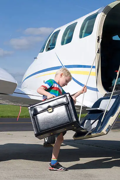 Photo of Child climbing the steps of a light aircraft with case