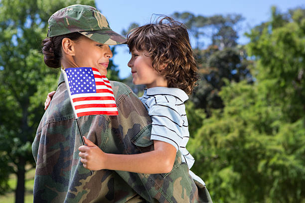 A female US soldier reuniting with her happy son Soldier reunited with her son on a sunny day veteran stock pictures, royalty-free photos & images