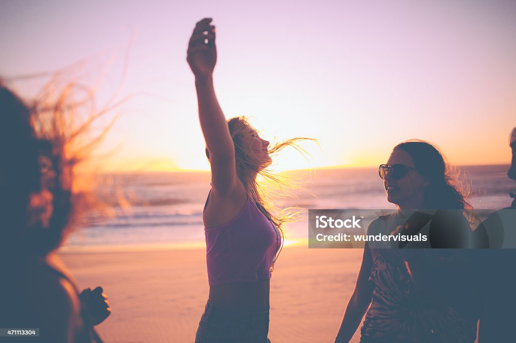 Chica siente libre en contra de un atardecer en la playa con amigos - Foto de stock de Puesta de sol libre de derechos