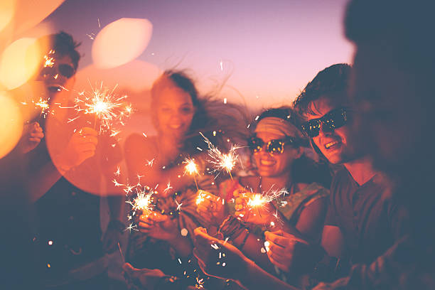 friends holding sparklers en un beachparty en crepúsculo - beach party friendship teenage girls fotografías e imágenes de stock